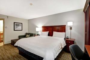 a hotel room with a large bed and a chair at Hampton Inn Beckley in Beckley