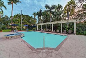 uma grande piscina com cadeiras e palmeiras em Hampton Inn & Suites Boynton Beach em Boynton Beach