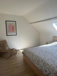 een slaapkamer met een bed en een stoel bij Le Refuge de Toine Gîte rural 3 épis in Chimay
