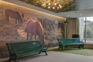 two benches in front of a mural of horses on a wall at Hilton Bournemouth in Bournemouth