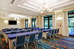 Hampton Inn & Suites Boynton Beach في بوينتون بيتش: قاعة المؤتمرات مع الطاولات والكراسي الزرقاء وتلفزيون بشاشة مسطحة