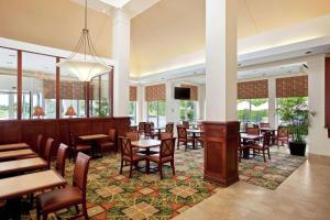 ein Restaurant mit Tischen, Stühlen und Fenstern in der Unterkunft Hilton Garden Inn Oakbrook Terrace in Oakbrook Terrace