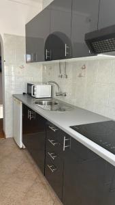a kitchen with a sink and a microwave at Hostel da Praia in Portimão