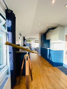 a camera on a tripod in a kitchen with blue cabinets at Polhawn Lookout, The Forgotten Chalet in Cawsand