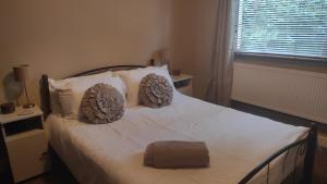 um quarto com uma cama com lençóis brancos e almofadas em Retreat by the Feale em Listowel