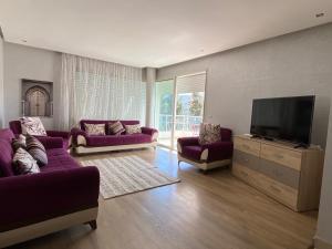 a living room with purple couches and a flat screen tv at Prestigia Golf city Bouskoura Apartment in Bouskoura