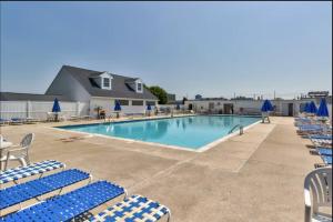 uma piscina com cadeiras azuis e brancas em Montego Bay - Atlantic 13300 em Ocean City