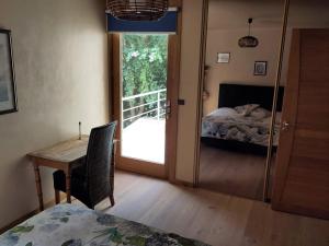 a bedroom with a bed and a desk and a window at B&B chez Frédérique et Norbert in Mogneneins