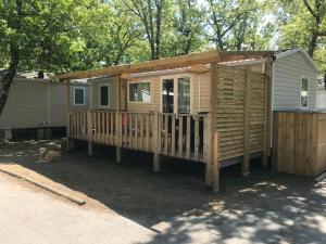 une petite maison avec une terrasse couverte et un chien se tenant à côté de celle-ci dans l'établissement Chaussy55, à Lagorce