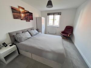 1 dormitorio con 1 cama blanca y 1 silla roja en North Colchester Homestay en Mile End
