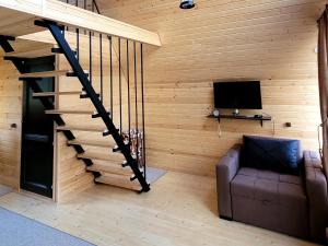 a living room with a staircase with a couch and a television at MTISGULI Cottages in Kazbegi