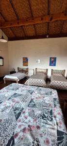 a room with three beds with a quilt on it at Pousada Caminho dos Ipês in Bocaina de Minas