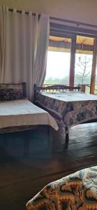 dwa łóżka w pokoju z oknem w obiekcie Pousada Caminho dos Ipês w mieście Bocaina de Minas