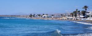 einen Strand mit blauem Wasser, Gebäuden und Palmen in der Unterkunft Casa Sun & Sea in Playa Honda