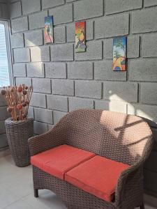 a wicker chair with a red bench in front of a brick wall at Rancho Ayala II in Santa Marta