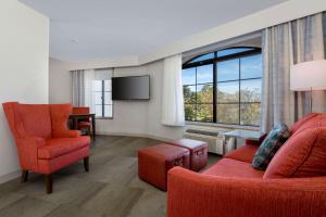 sala de estar con muebles de color rojo y ventana grande en Hampton Inn Santa Barbara/Goleta, en Santa Bárbara