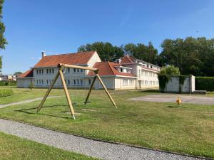 a swing set in the grass in front of a house at Dahlia 107 - zonnig en volledig uitgerust appartement in De Haan