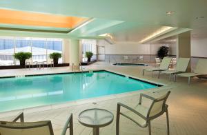 - une grande piscine dans un hôtel avec des chaises et des tables dans l'établissement Embassy Suites by Hilton Washington DC Chevy Chase Pavilion, à Washington