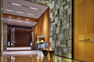 un vestíbulo con una pared de azulejos de cristal en la pared en Hilton Garden Inn Shenzhen Bao'an en Bao'an
