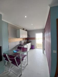 uma cozinha com uma mesa de vidro e cadeiras roxas em Casa do Portão Azul - Salmonete em Atouguia da Baleia