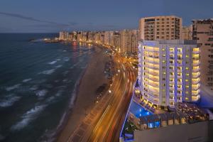 Hilton Alexandria Corniche Hotel في الإسكندرية: اطلالة على شاطئ بالليل مع مباني