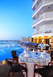 Hilton Alexandria Corniche Hotel في الإسكندرية: مطعم بطاولات وكراسي بجانب مسبح