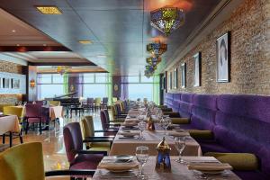 una larga fila de mesas en un restaurante con cabinas púrpuras en Hilton Alexandria Corniche Hotel, en Alejandría