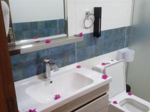 Wadi Rum Gulf camp في العقبة: حمام مع حوض ومرحاض مع الزهور الزهرية