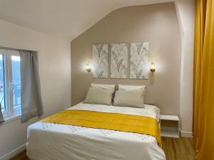 una camera con un letto con una coperta gialla di Le Cocon - logement 4 personnes - Neuf - Wifi a Le Bourget