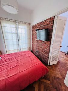 - une chambre avec un lit rouge et un mur en briques dans l'établissement Hermoso Departamento en Belgrano R para 3 personas, à Buenos Aires