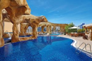 uma piscina num resort com uma parede de pedra em Hilton Beirut Habtoor Grand Hotel em Beirute