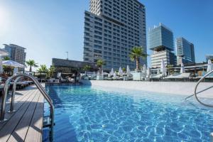 a large swimming pool in a city with tall buildings at Hilton Diagonal Mar Barcelona in Barcelona