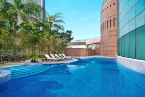 uma piscina com espreguiçadeiras e um edifício em Hilton Beirut Metropolitan Palace Hotel em Beirute