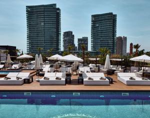 - une piscine avec des chaises longues et des parasols dans l'établissement Hilton Diagonal Mar Barcelona, à Barcelone