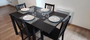 a black table with chairs and plates and wine glasses at TOK TOK A6 - Appartement 2Ch Toutes commodités in Annoeullin +4 photos