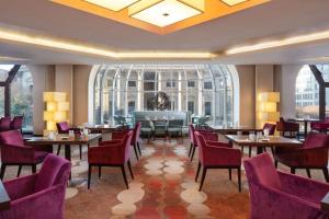 um restaurante com mesas e cadeiras e uma grande janela em Hilton Berlin em Berlim