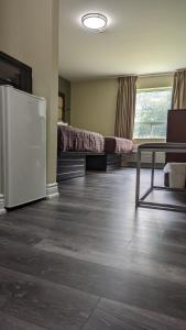 a room with a bed and a table and a refrigerator at Knights Inn Bracebridge in Bracebridge