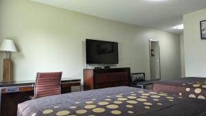 a hotel room with a bed and a flat screen tv at Knights Inn Bracebridge in Bracebridge +15 photos