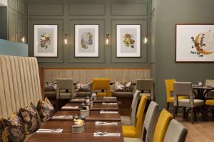 a restaurant with wooden tables and yellow chairs at Hilton Birmingham Metropole Hotel in Bickenhill +166 photos