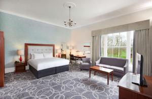 格洛斯特Hilton Puckrup Hall Hotel & Golf Club, Tewkesbury的一间带床和客厅的酒店房间