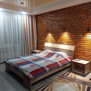 a bedroom with a bed and a brick wall at Vintage гостиница in Shchūchīnsk