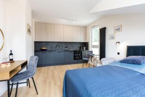 a bedroom with a bed and a desk and a kitchen at Apartament Olsztyn Centrum in Olsztyn