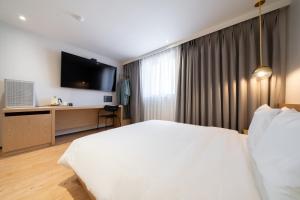 a bedroom with a white bed and a television at Hotel 23 in Ulsan