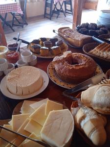 una mesa llena de diferentes tipos de pan y repostería en POUSADA BELA HELENA, en Visconde De Maua