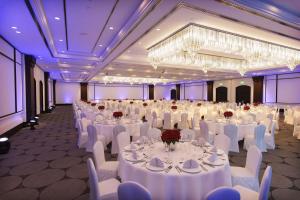 a banquet hall with white tables and chairs and a chandelier at Hilton Paris Charles De Gaulle Airport in Roissy-en-France
