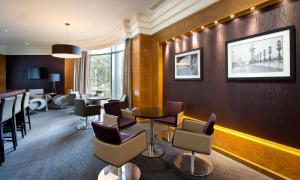 a waiting room with chairs and a table and a bar at Hilton Paris Charles De Gaulle Airport in Roissy-en-France