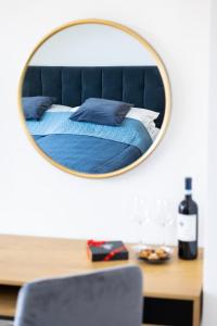 a mirror reflecting a bed with blue sheets and a bottle of wine at Apartament Olsztyn Centrum in Olsztyn