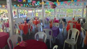 uma sala cheia de mesas e cadeiras vermelhas e roxas em ParadiseKamp Açutuba em Iranduba
