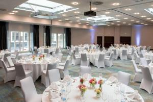 a banquet hall with white tables and white chairs at Hilton Cologne in Cologne