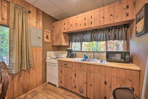 cocina con armarios de madera, fregadero y microondas en Lucas McCain Cabin 5 Mi to Raystown Lake Launch!, en Huntingdon